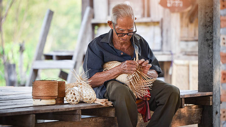 An Indonesian man weaving bamboo to make small baskets.