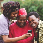 Three women looking at a phone.