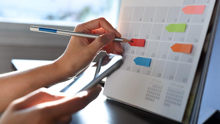 A hand marking a date on a calendar