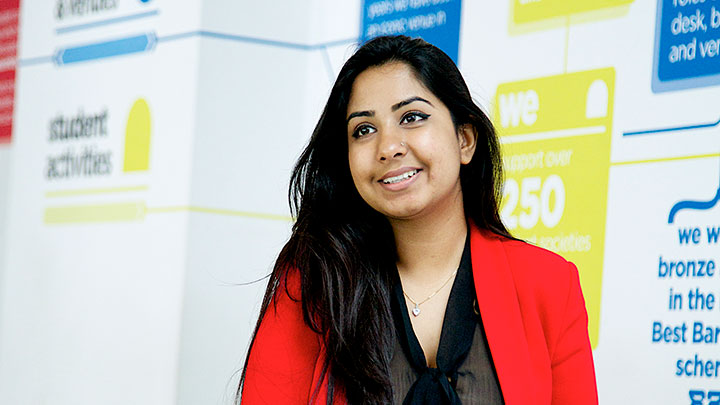 A student in a red jacket, smiling into the distance.