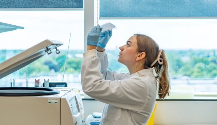 An MCRC postgraduate researcher in the lab, pipetting.